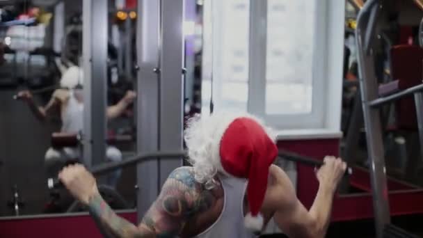 Fitnesstrainer Weihnachtsmann im Fitnessstudio am Simulator . — Stockvideo