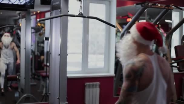 Fitnesstrainer Weihnachtsmann im Fitnessstudio am Simulator . — Stockvideo