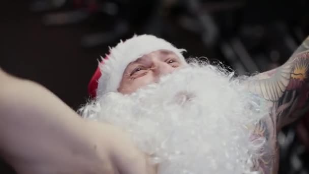 Instruktor fitness Santa Claus w sali gimnastycznej na symulatorze, twarz zbliżenie. — Wideo stockowe