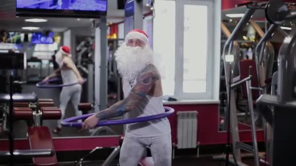 Instructor de fitness Santa Claus en el gimnasio girando hula hoop . — Vídeos de Stock