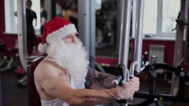 Fitness instruktor Santa Claus v tělocvičně na simulátoru.