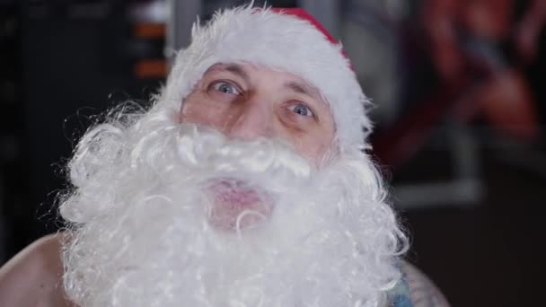 Moniteur de fitness Père Noël dans la salle de gym sur le simulateur, face close-up . — Video