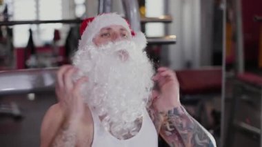 Bacaklarını simülatör spor salonunda fitness eğitmeni Noel Baba eğitiyor.