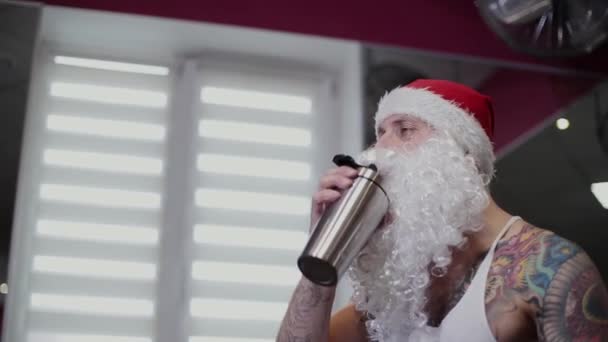 Fitness instructeur Santa Claus in de sportschool water drinkt uit een shaker en boos. — Stockvideo