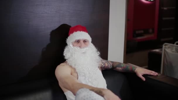 Istruttore di fitness Babbo Natale in palestra appoggiato su un divano in pelle . — Video Stock