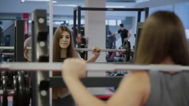 Wanita yang sangat cantik berjongkok dengan barbel di bahunya . — Stok Video