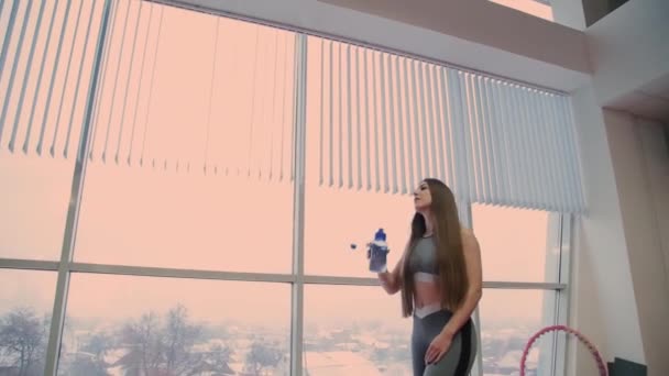 Mycket vacker kvinna dricker vatten från en shaker efter träning. — Stockvideo
