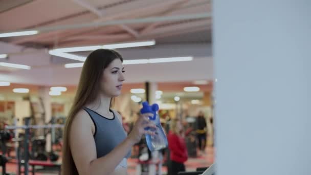 Donna molto bella che si allena sul tapis roulant in palestra e acqua potabile . — Video Stock