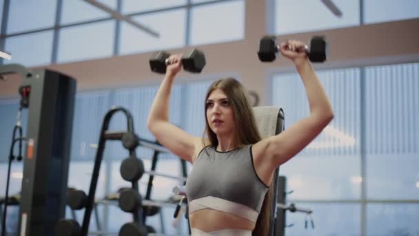 Mujer de fitness muy hermosa haciendo ejercicio con pesas en el gimnasio . — Vídeo de stock