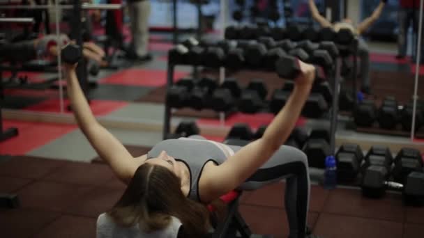 Très belle femme fitness faisant de l'exercice avec des haltères dans la salle de gym . — Video