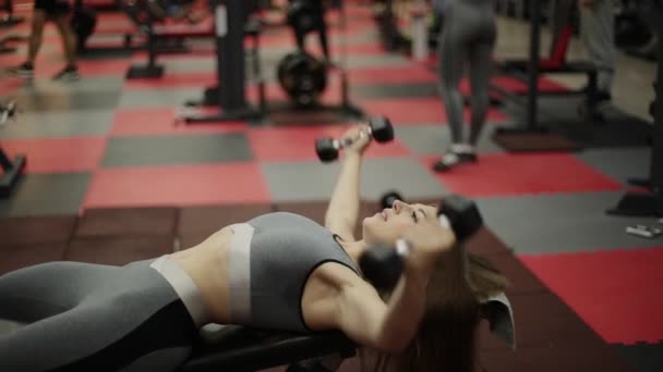 Mujer de fitness muy hermosa haciendo ejercicio con pesas en el gimnasio . — Vídeos de Stock