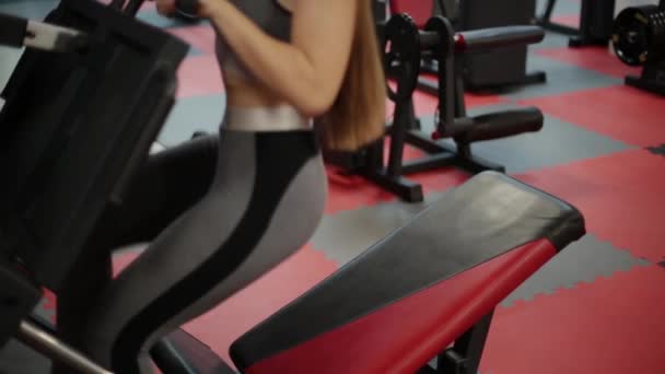 Mujer fitness muy hermosa entrena sus piernas en el simulador en el gimnasio . — Vídeos de Stock