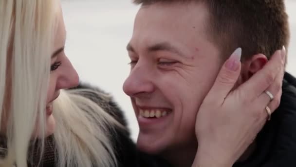 Bela jovem casal sentado em um banco de abraços falando e sorrindo em um parque de inverno da cidade . — Vídeo de Stock