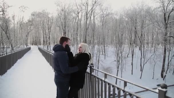 Hermosa pareja joven abrazándose y hablando en un parque de invierno de la ciudad . — Vídeos de Stock