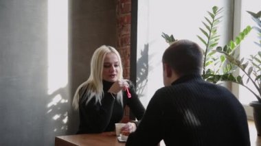 Kahve içme ve birbirine bakarak tatlı yeme bir kafede oturmuş aşk çift.
