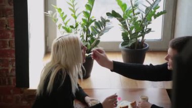 Kahve içme ve birbirine bakarak tatlı yeme bir kafede oturmuş aşk çift.