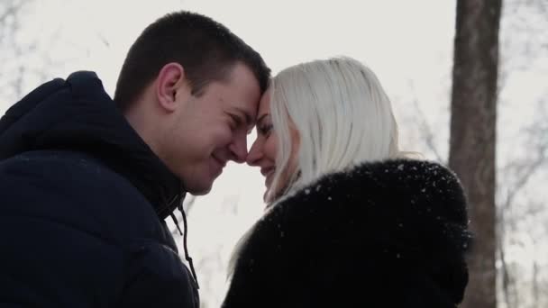 Hermosa pareja joven sonriéndose a la luz del sol. Ciudad parque de invierno . — Vídeo de stock