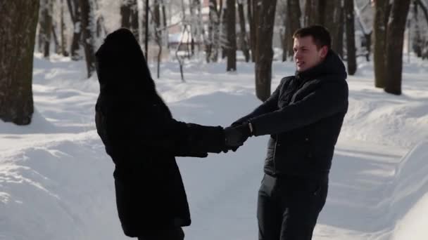 Krásný mladý pár, drželi se za ruce a spinning. Městský zimní park. — Stock video
