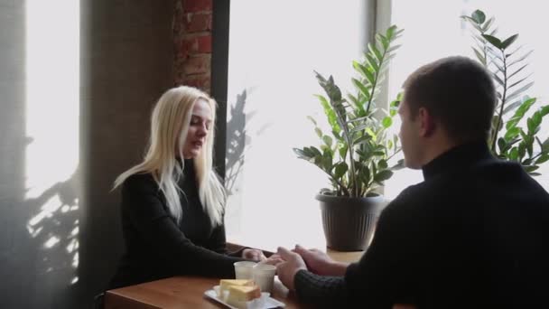 Szerelmes pár ül egy kávézóban, beszél és néztek egymásra. — Stock videók