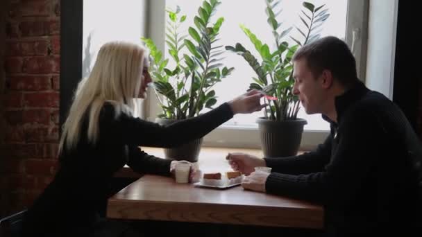 Amor pareja sentado en un café comiendo postre beber café y mirándose el uno al otro . — Vídeos de Stock