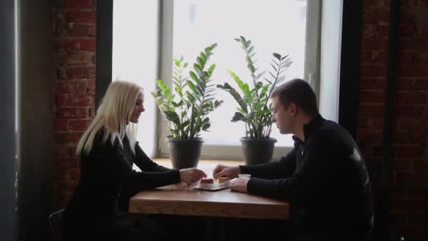 Miłość para siedząc w kawiarni jedzenie deser, picia kawy i patrząc na siebie. — Wideo stockowe