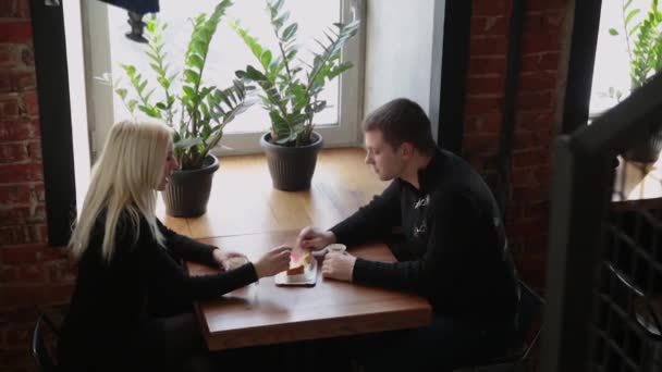 Amor pareja sentado en un café comiendo postre beber café y mirándose el uno al otro . — Vídeos de Stock