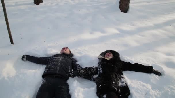 Όμορφο νεαρό ζευγάρι εκμετάλλευση τα χέρια σχετικά με το χιόνι και έχοντας διασκέδαση. Χειμερινό πάρκο της πόλης. — Αρχείο Βίντεο