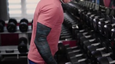 Sportif yakışıklı dumbbell pazı salonunda eğitim.