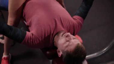 Çok güzel ve seksi fitness modeli bir adam jimnastik salonu için sıra sıkıştırma gerçekleştirmek için yardımcı olur.