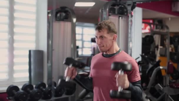 Snygg sportig man utbildning hantel biceps på gymmet. — Stockvideo