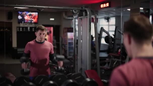 Guapo deportista entrenamiento manivela bíceps en el gimnasio . — Vídeos de Stock