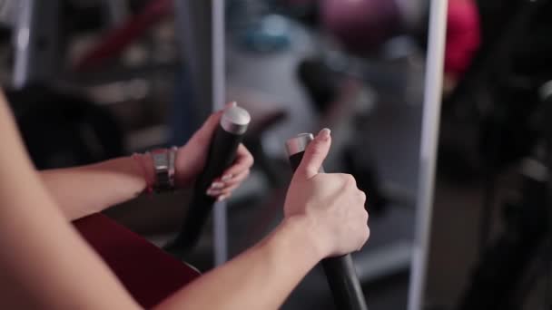 Mycket vacker och sexig fitness modelltåg coaching baksidan av låret på en simulator i gymmet. Händer på nära håll — Stockvideo