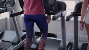 Çok güzel ve seksi fitness modeli ve man eğitim salonunda treadmill vardır.