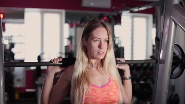 Very beautiful and sexy fitness model trains the legs with an athletic barbell in the gym. — Stock Video