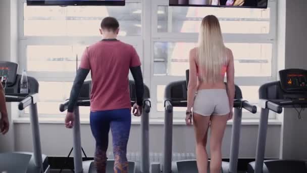 Muy hermoso y sexy modelo de fitness y el hombre están entrenando en la cinta de correr en el gimnasio . — Vídeo de stock