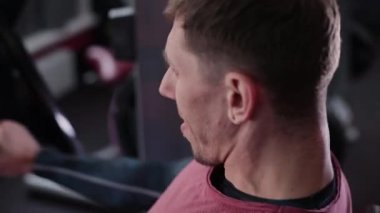 Adam atletik ve çekici bir simülatör spor salonunda göğüs kasları trenler.