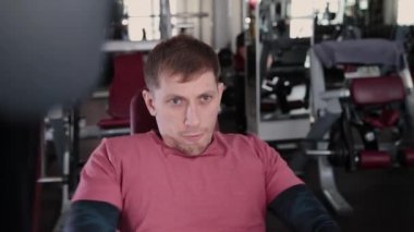 Adam atletik ve çekici bir simülatör spor salonunda göğüs kasları trenler