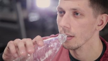 Atletik ve çekici bir adam içme suyu bir şişe içinde jimnastik salonu.