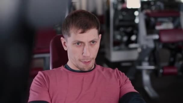 Hombre atlético y atractivo entrena los músculos pectorales en un simulador en el gimnasio . — Vídeos de Stock