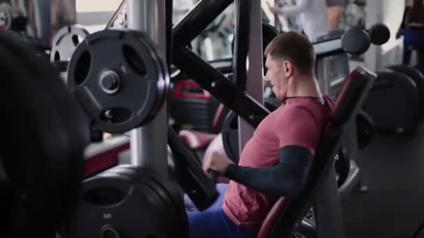 Hombre atlético y atractivo entrena los músculos pectorales en un simulador en el gimnasio . — Vídeo de stock