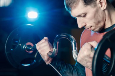 Yakışıklı atletik erkek trenler pazı halter salonunda.