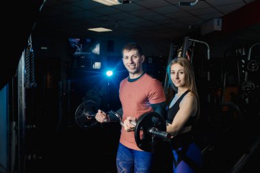 Yakışıklı atletik eğitim pazı halter jimnastik salonu kadın bir antrenör yardımıyla.