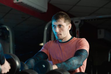 Yakışıklı atletik erkek dumbbells raflar daha fazla eğitim için gelen spor salonunda alır..