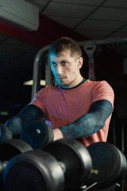 Yakışıklı atletik erkek dumbbells raflar daha fazla eğitim için gelen spor salonunda alır..