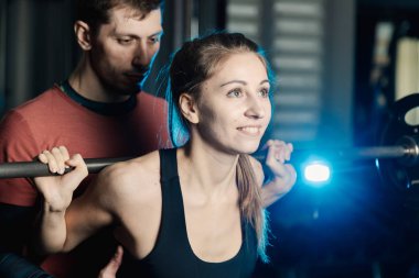 Yakışıklı atletik adam güzel bir kız için hiç bir şey ile bir halter salonunda omuzlarında yardımcı olur.