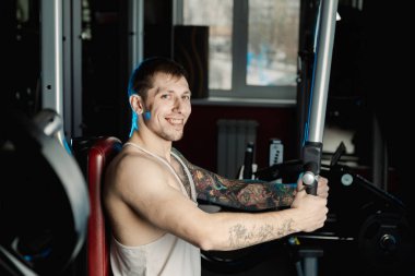 Göğüs kasları bir simülatör spor salonunda yakışıklı atletik erkek trenler.