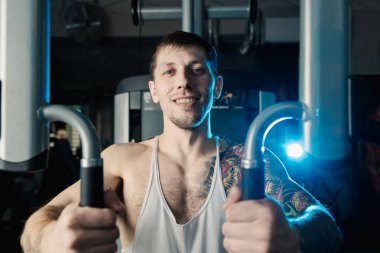 Göğüs kasları bir simülatör spor salonunda yakışıklı atletik erkek trenler.