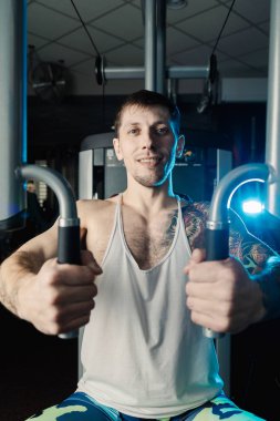 Göğüs kasları bir simülatör spor salonunda yakışıklı atletik erkek trenler.