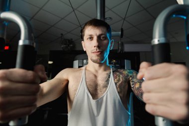 Göğüs kasları bir simülatör spor salonunda yakışıklı atletik erkek trenler.