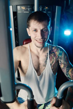 Göğüs kasları bir simülatör spor salonunda yakışıklı atletik erkek trenler.